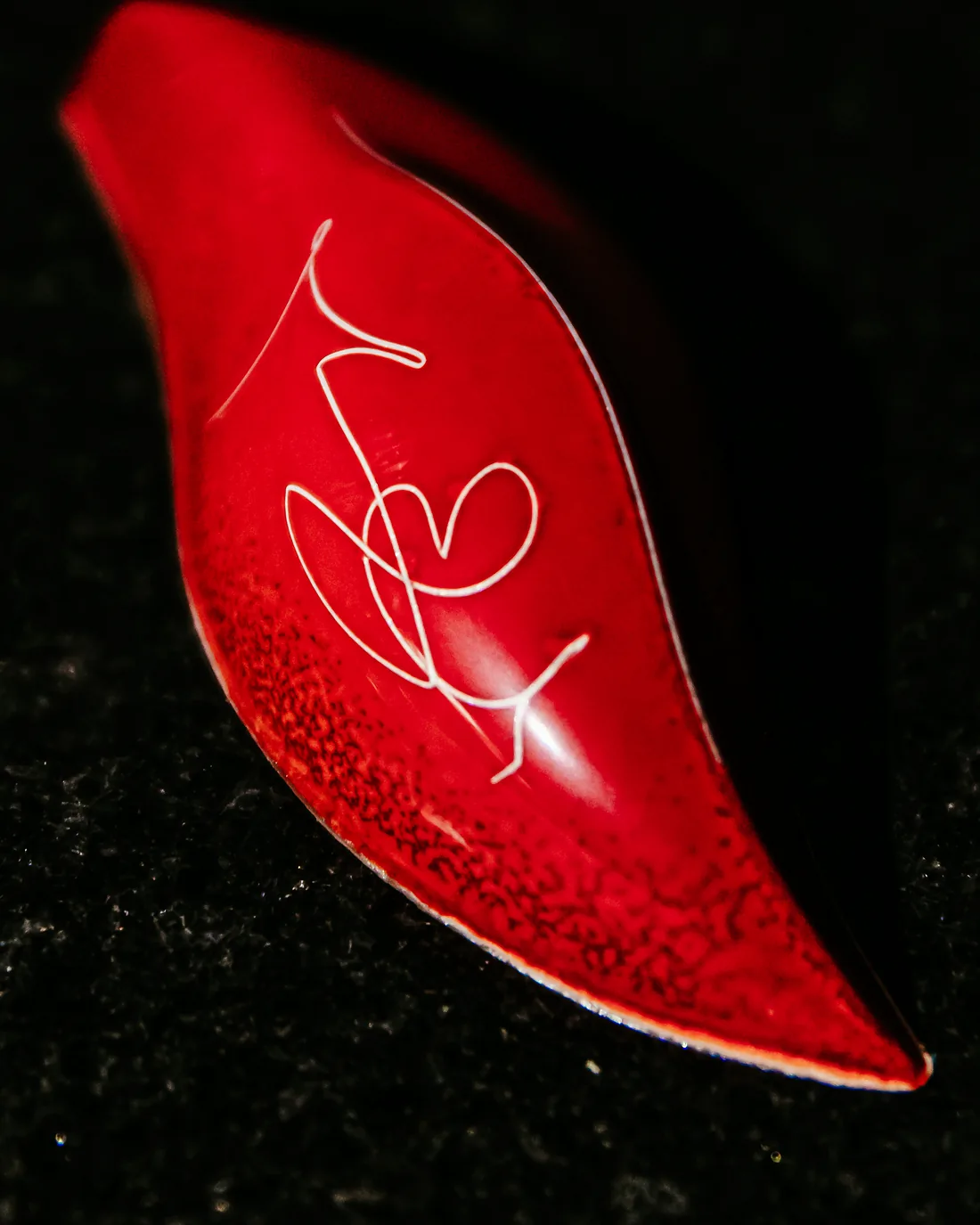A red lip-shaped praline with hand-painted white lines
