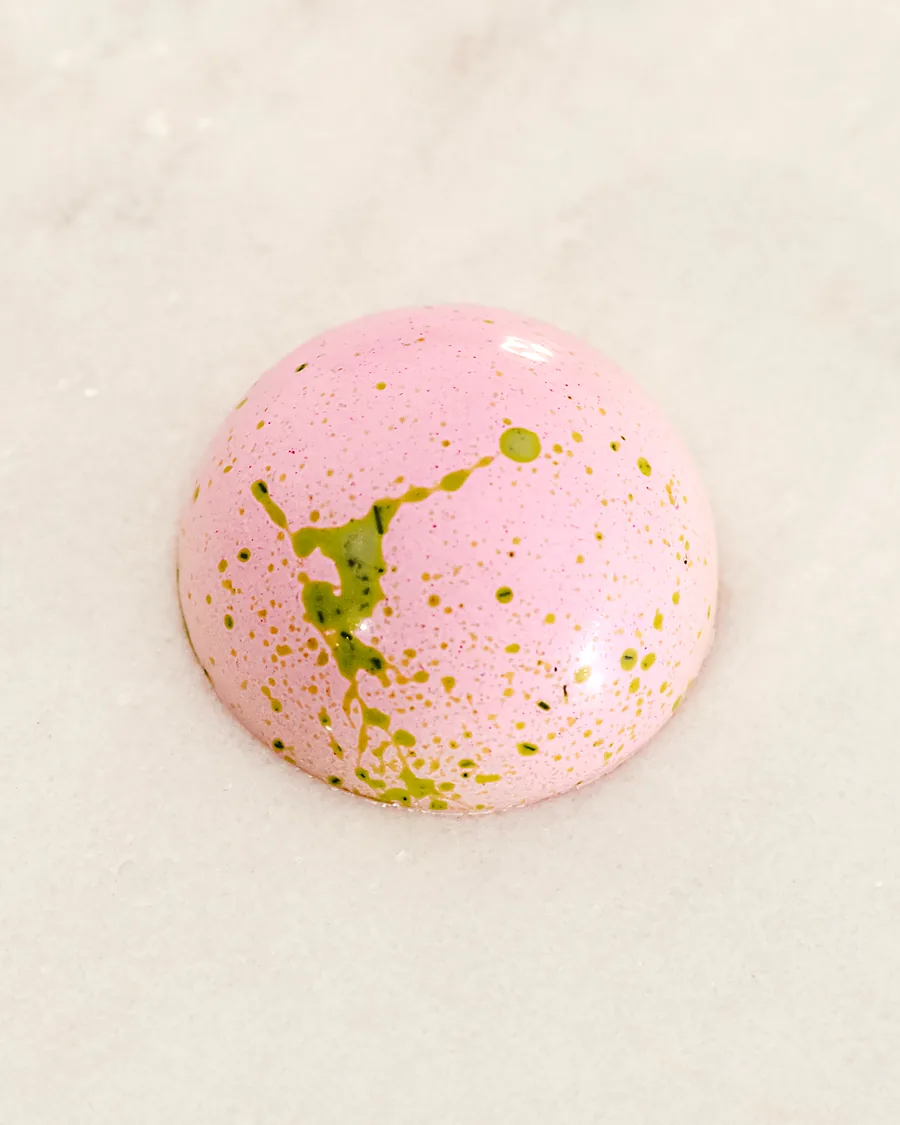 A pink praline with green speckles, raspberry ganache
